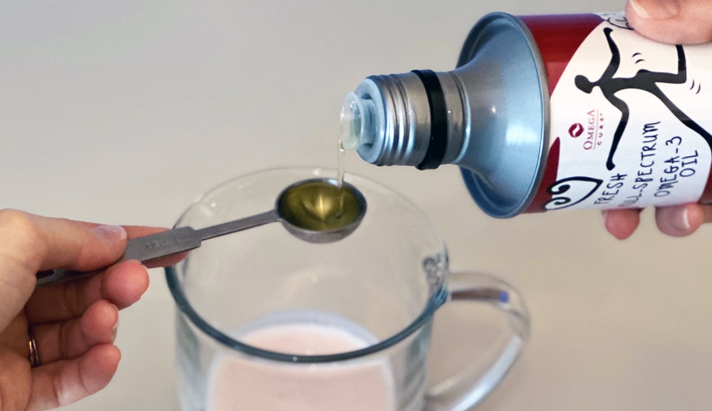 Liquid fish oil being poured onto a measuring spoon