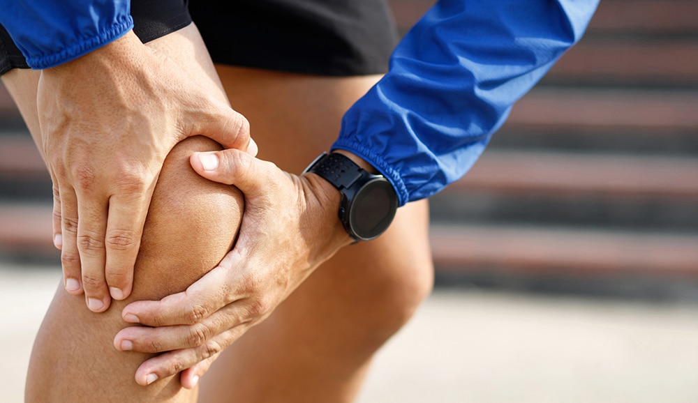 close up of a person holding onto their knee representing joint pain