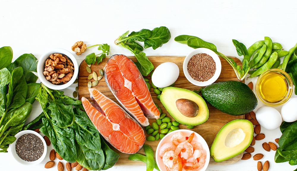 a plate of oily fish, avocados, shrimp, nuts, and leafy greens high in omega 3 fatty acids