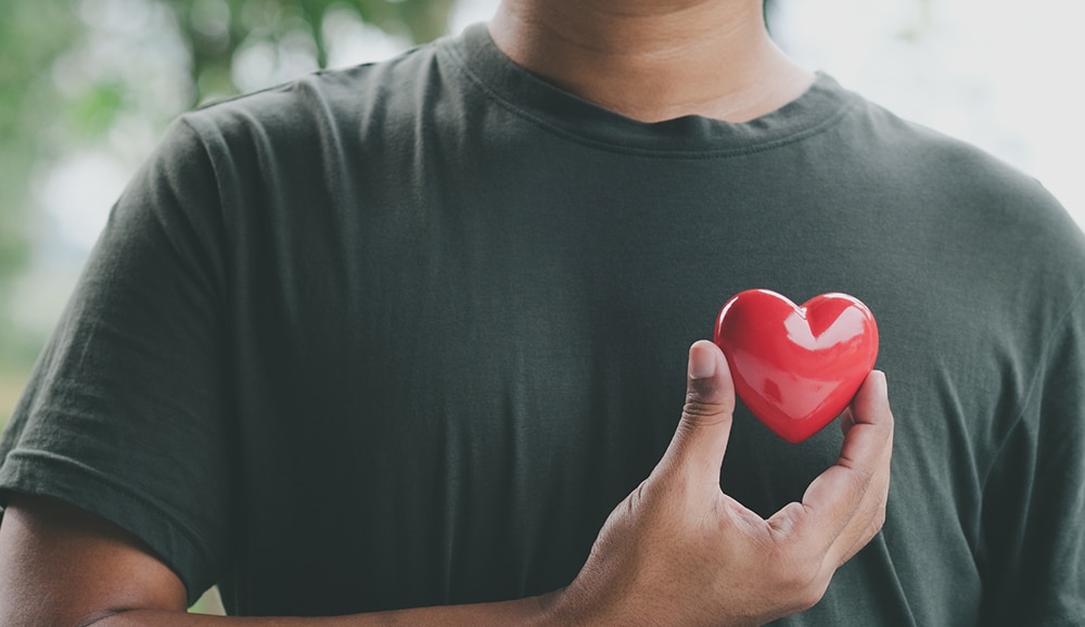 a person holding a heart over their chest