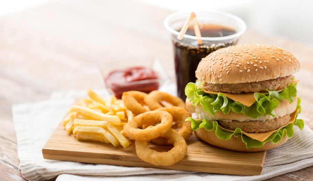 a burger, fries, onion rings, and a soda