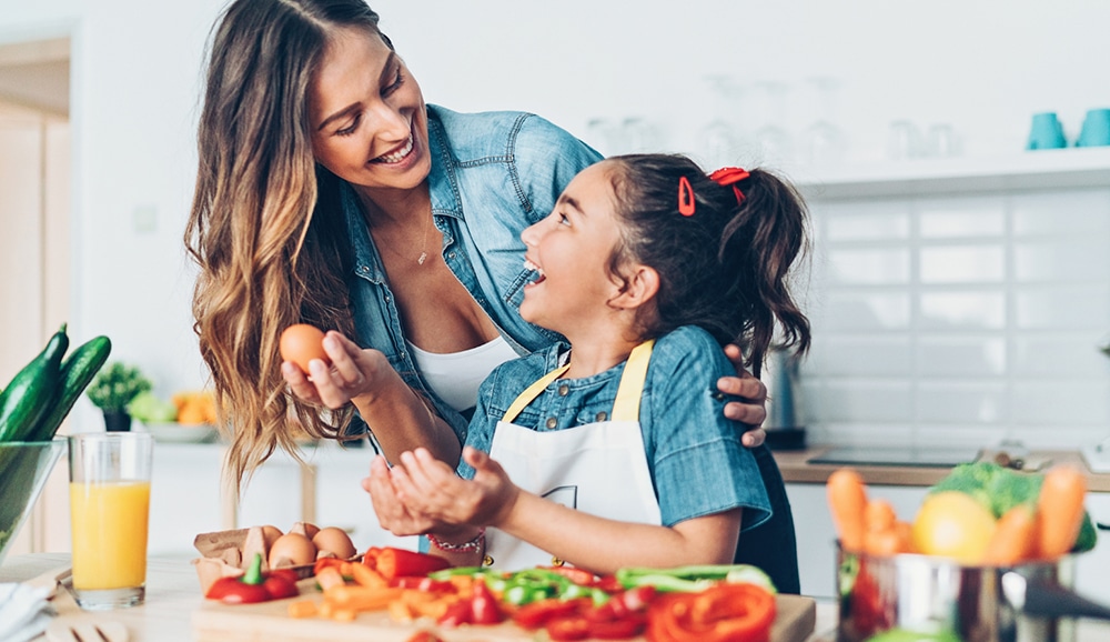 a mother and daughter preparing food together in the kitchen