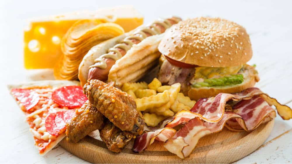 picture of greasy foods. Hot dog, burger, wings.