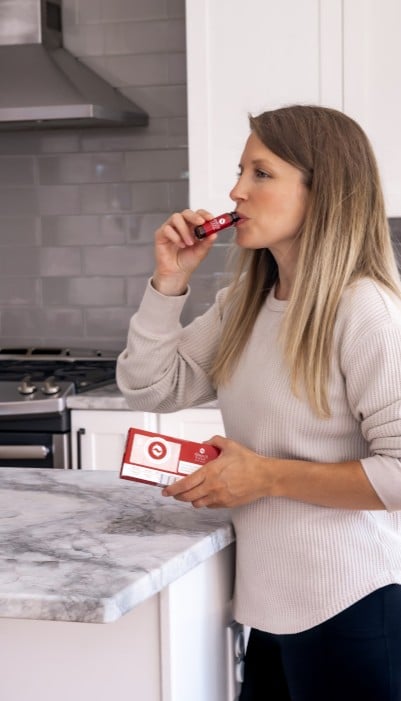 Woman taking vial of liquid fish oil out of refrigerator